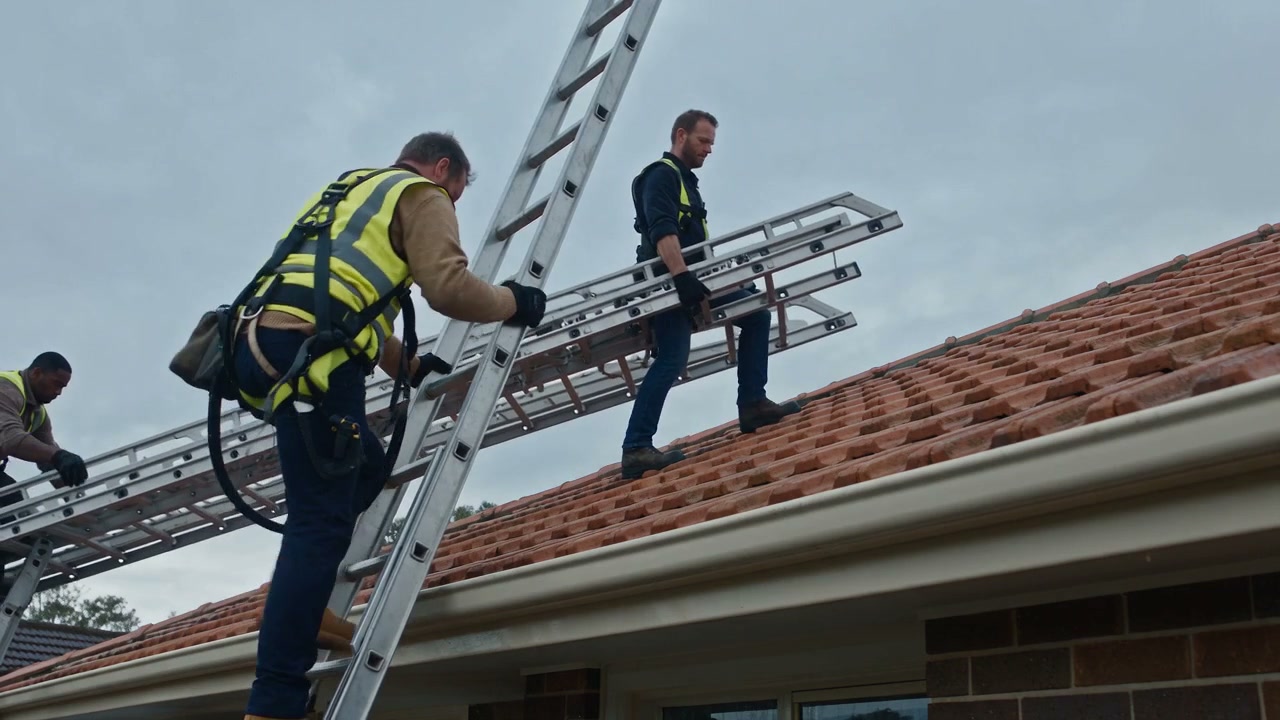 Two of the crew setting up ladders and safe roof access, harnessed and in hi-vis, from the film