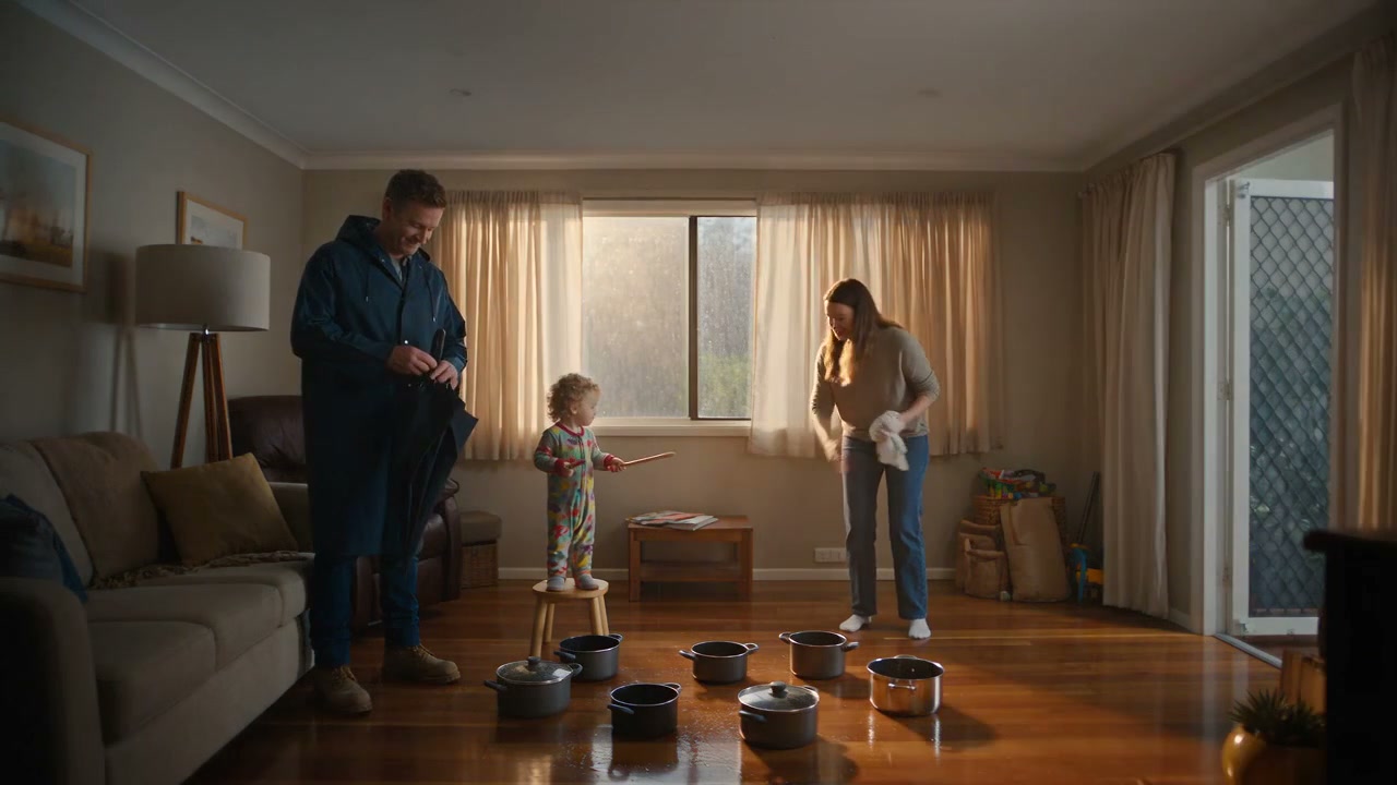 A dry, warmly lit lounge room after the repair, pots and buckets put away, from the film